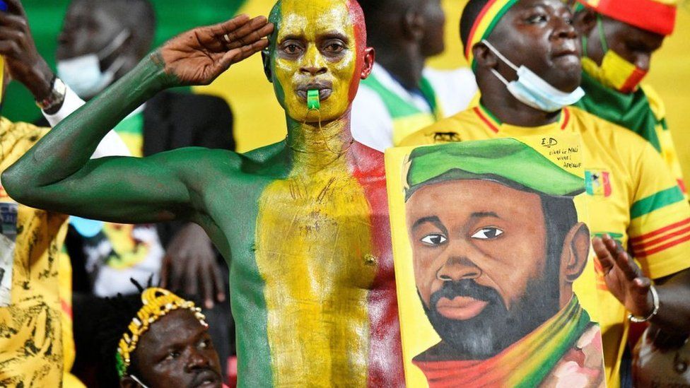 A Mali supporter holds a portrait of Malian junta leader Colonel Assimi Goita before the Africa Cup of Nations (CAN) 2021 round of 16 football match between Mali and Equatorial Guinea at Limbe Omnisport Stadium in Limbe on January 26, 2022
