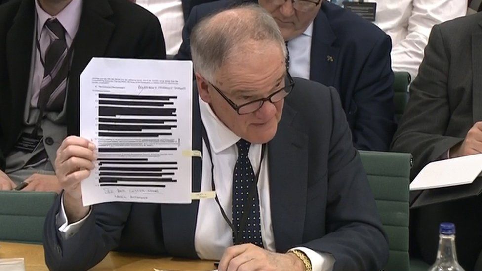 Henry Staunton holding up redacted document
