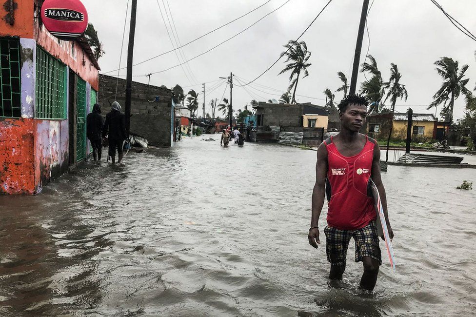 A man walks down a flooded road