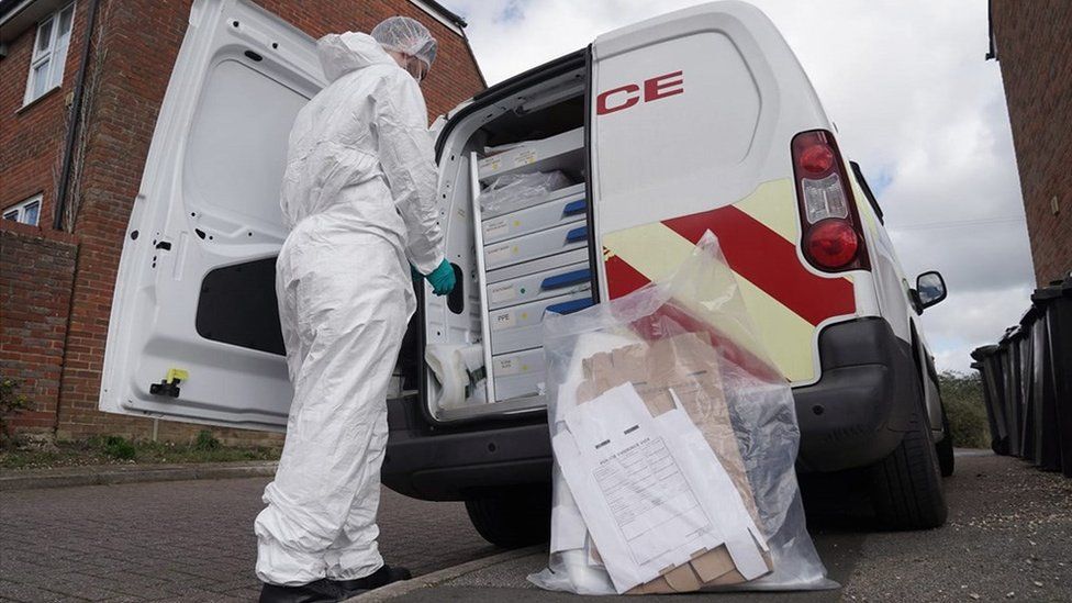 Police forensic officer loading evidence into a van