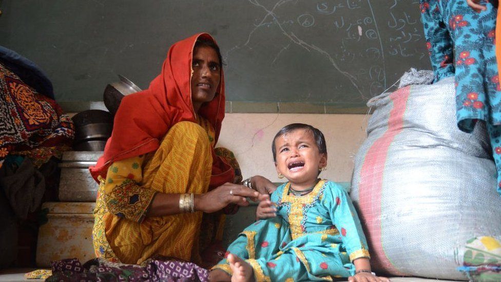 Displaced people wait for assistance after fleeing their homes in Karachi province