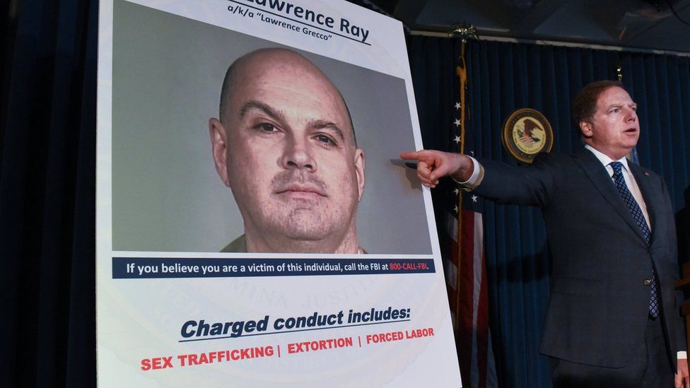 Прокурор Манхэттена США Джеффри Берман указывает на фотографию Лоуренса Рэя после объявления обвинений в Нью-Йорке в феврале 2020 года.