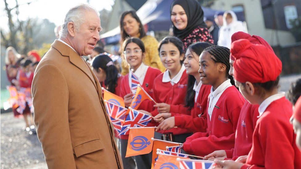 King Charles III speaks with local schoolchildren during a visit to the newly built Guru Nanak Gurdwara in Luton
