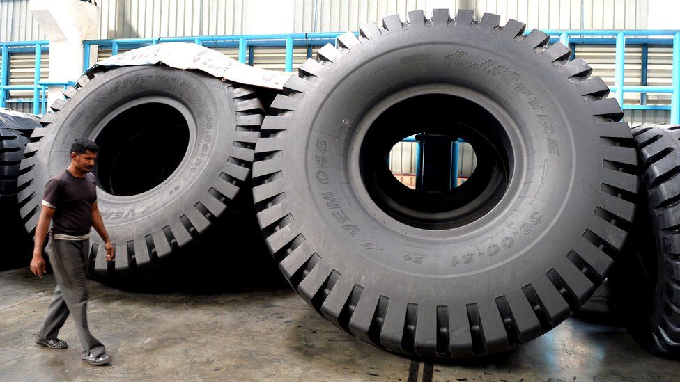 An Indian employee walks past tyres at the JK Tyre and Industries