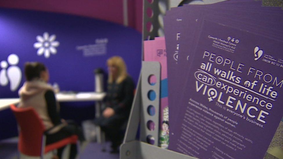 Blurred shot of domestic violence victim and reporter with domestic violence information leaflet in foreground