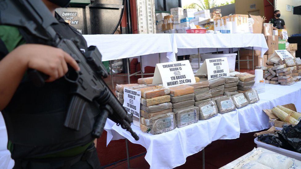 Armed agents of the Philippine Drug Enforcement Agency (PDEA) stand guard next to seized illegal drugs including bricks of cocaine