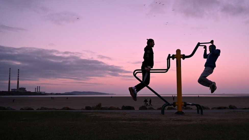 Two young people use outdoor gym equipment in Dublin