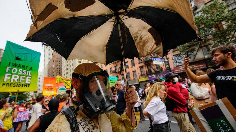 A person wearing a costume looks on as activists mark the start of Climate Week in New York during a demonstration
