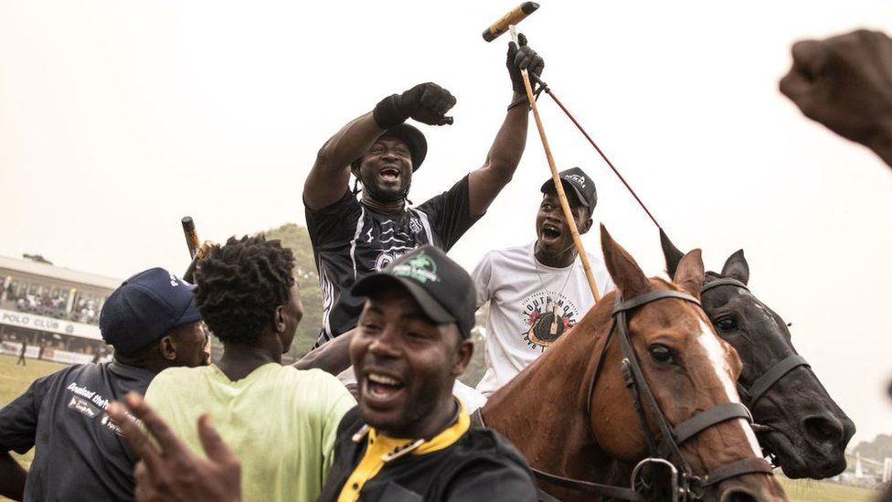 Конюхи и игрок празднуют на поле победу своей команды в финале Международного турнира по поло в Лагосе, 19 февраля 2023 г.