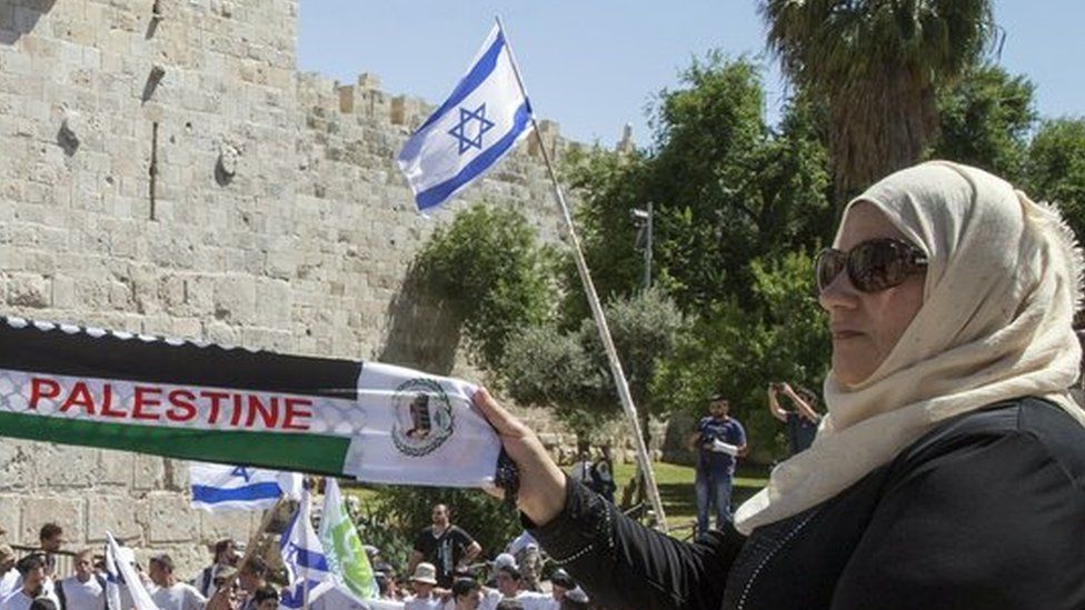 Palestinian woman holds 'Palestine' scarf in front of pro-Israel rally in Jerusalem (file photo)