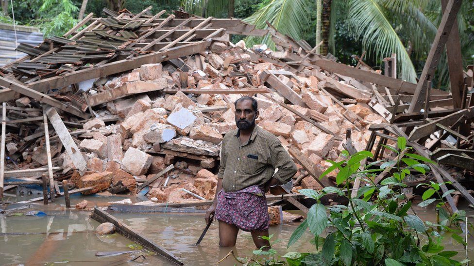 Ajith Prasad stands in front of the rubble of his house on the outskirts of Kozhikode district