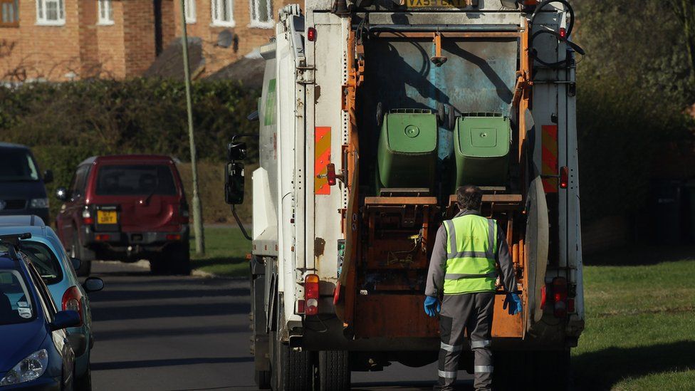 Refuse collectors empty green 'wheelie' bins