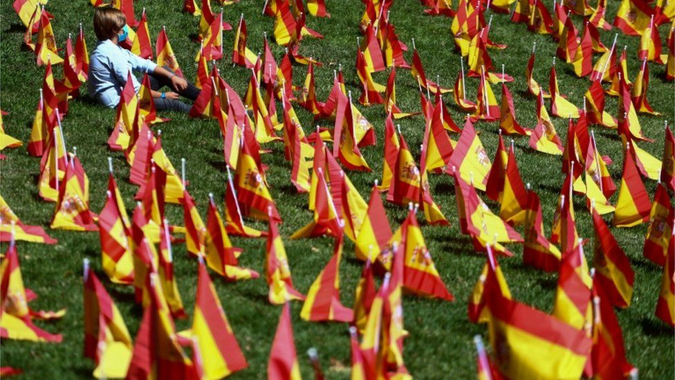 A boy sits among dozens of Spanish flags in Madrid