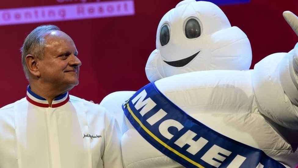 Joel Robuchon (L) stars poses with the tyre company's mascot during the Michelin Guides Award ceremony in Singapore on 21 July 2016