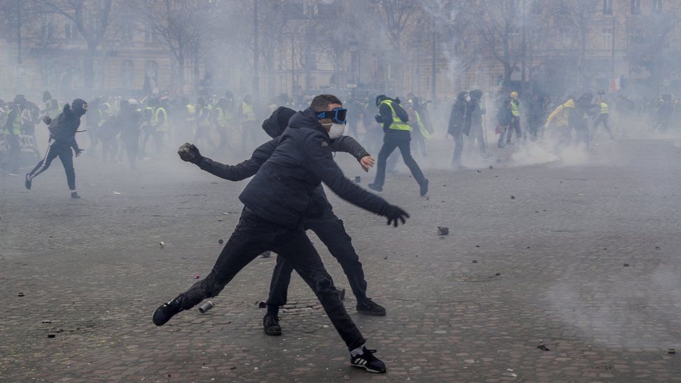 Demonstrators throw cobblestones at riot police forces during clashes near the Arc de Triomphe in Paris on March 16, 2019