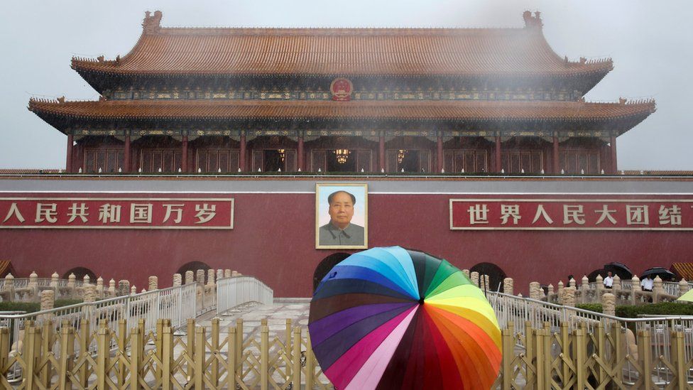 A tourist holds an umbrella as he stands in front of the Tiananmen Gate and a giant portrait of Chinese late Chairman Mao Zedong on a day of heavy rain in Beijing, China, July 20, 2016