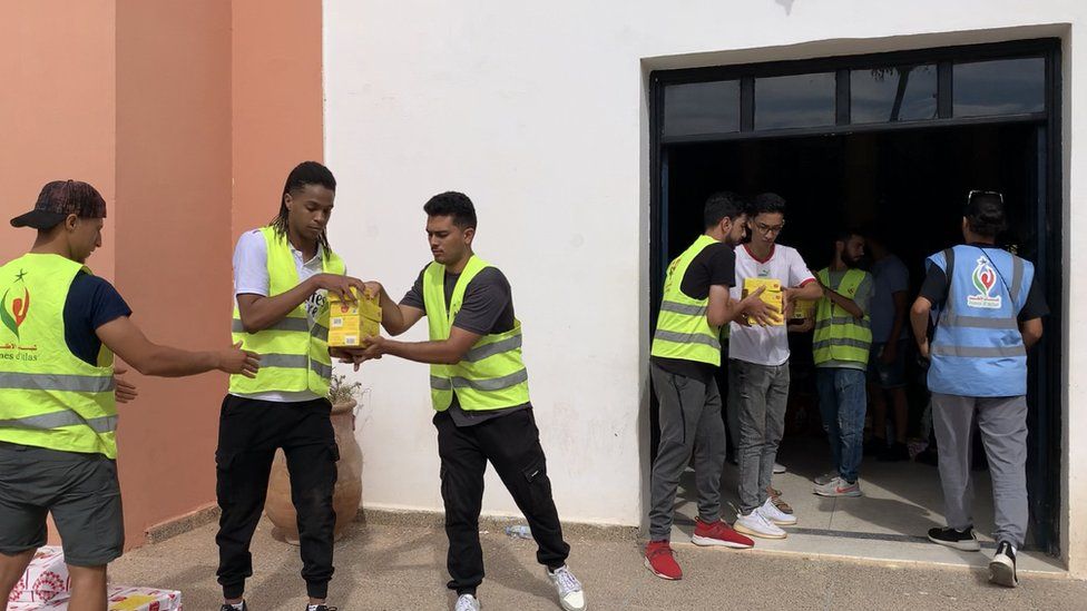 A group of young volunteers pass aid parcels to each other