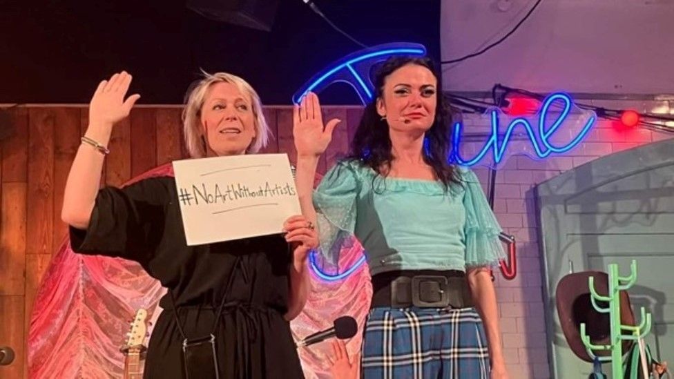 Artists behind June Carter Cash: The Woman, Her Music and Me standing together on stage with a sign saying #noartwithoutartists