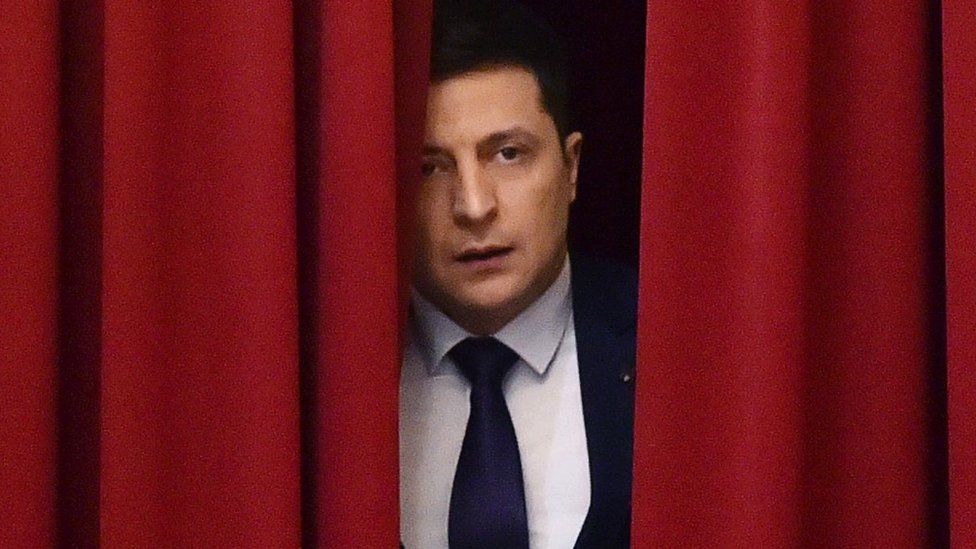 Volodymyr Zelensky stands behind a red curtain during filiming in March 2019