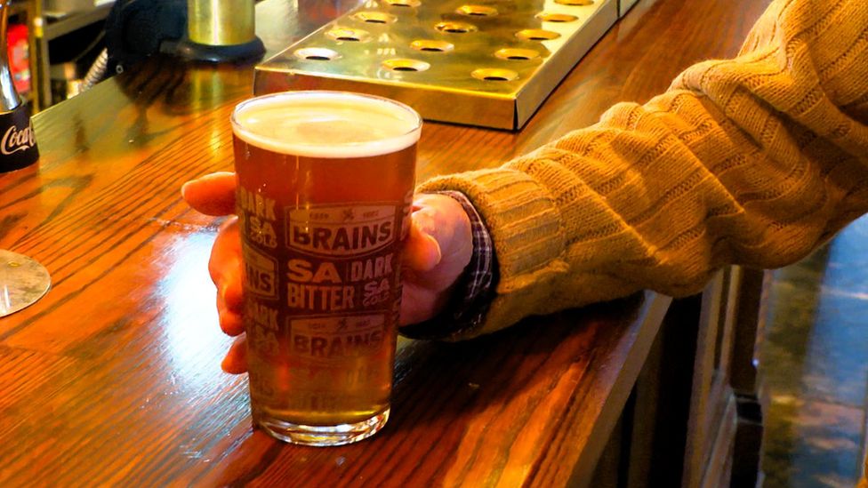 A pint of Brains being held on a bar