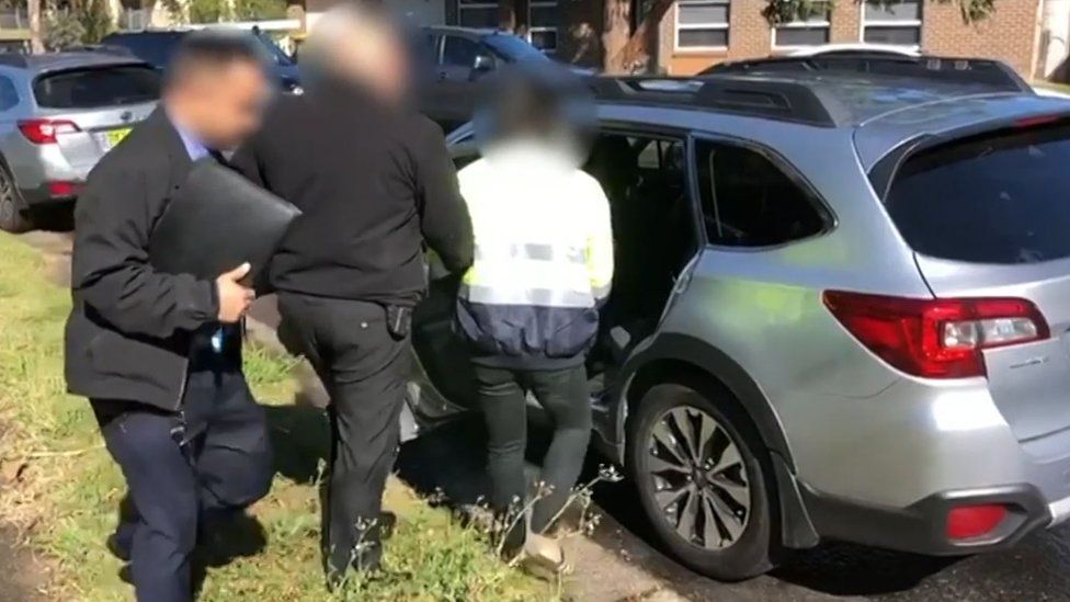 Police arresting a man in Sydney escort him into a police car