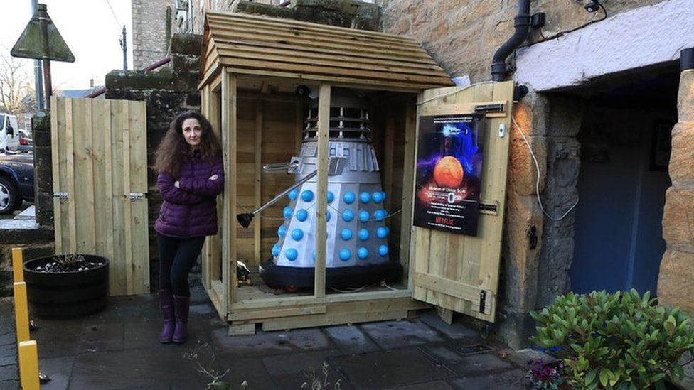 Museum co-owner Lisa Cole stands next to the Dalek and shed