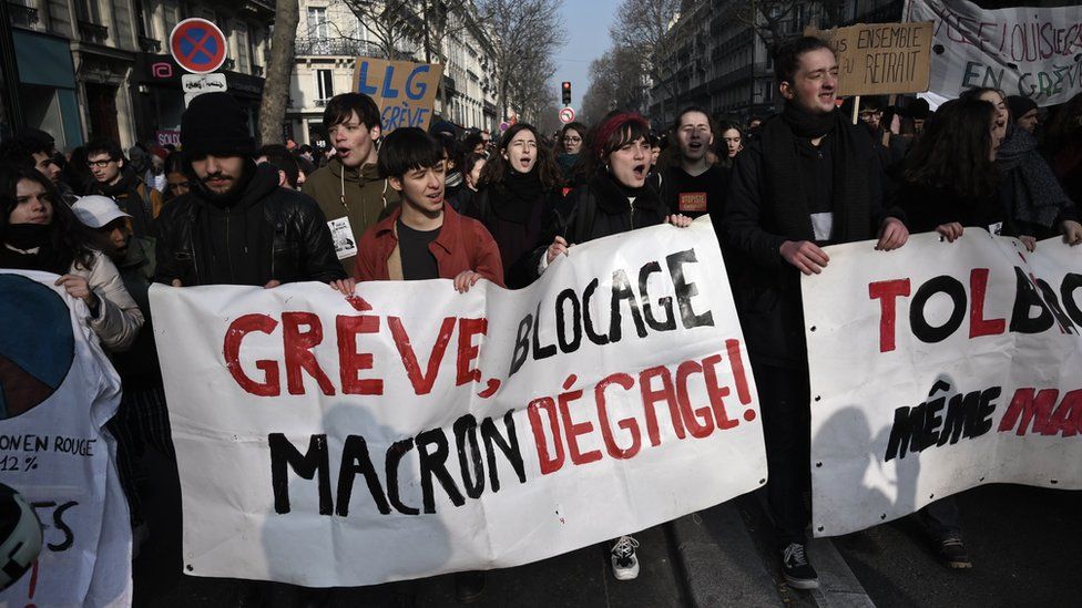A protester holds banner reading "Strike, blockade: Macron get out" during a demonstration in Paris on January 24, 2020