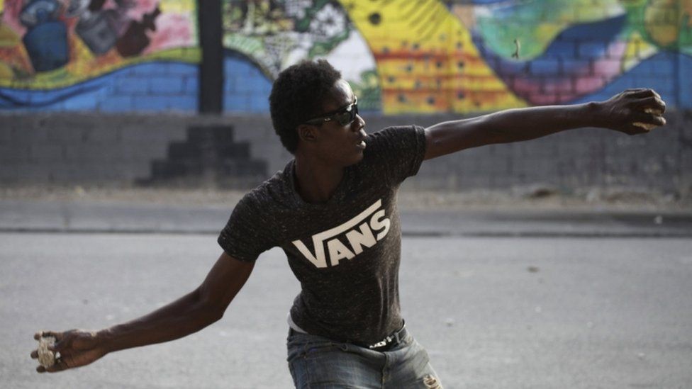 Opposition protester hurls a stone in Port au Prince