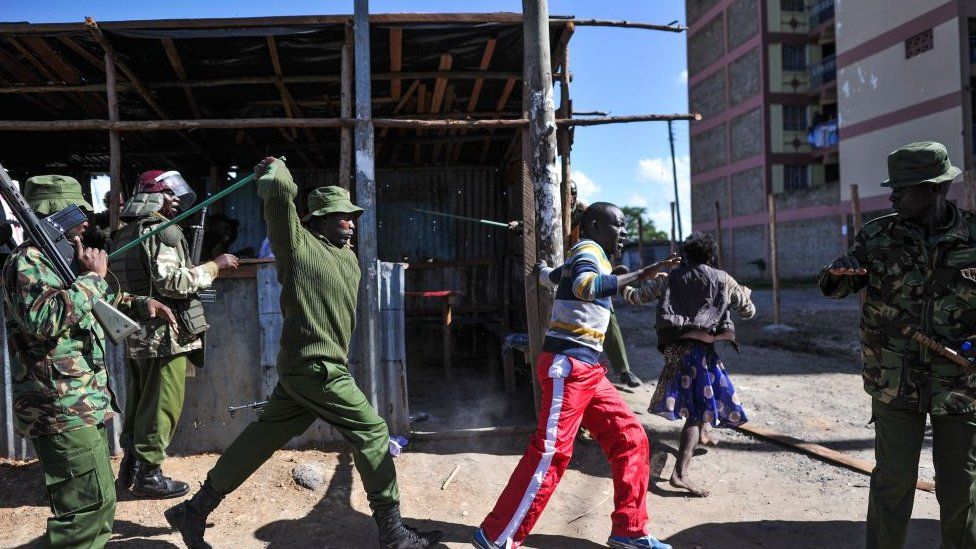 An anti-riot policeman beats a man with a stick as police flushes out opposition supporters, who had taken cover in a shack to escape teargas, during demonstrations in the Umoja suburb of Nairobi on November 28, 2017, following a denial of permission by police to the National Super Alliance (NASA) leader to hold a rally concurrently to the inauguration of the country's new president.