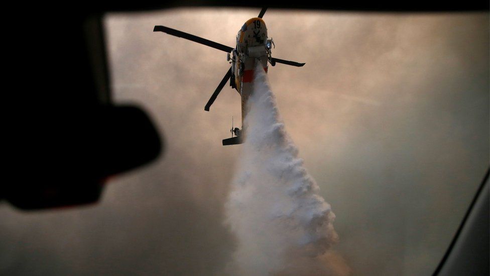 A helicopter makes a water drop as the Woolsey Fire burns in Malibu