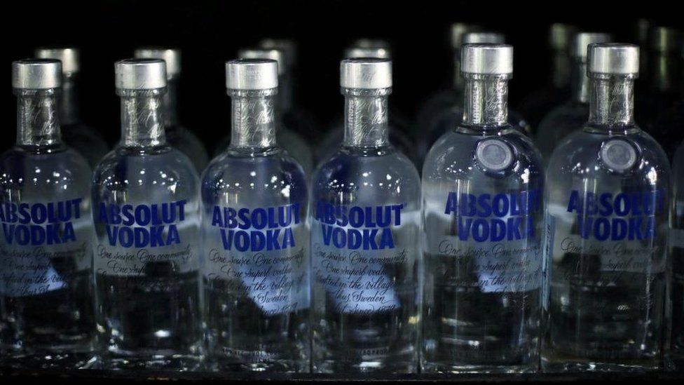 Numerous absolut vodka bottles lined up next to each other