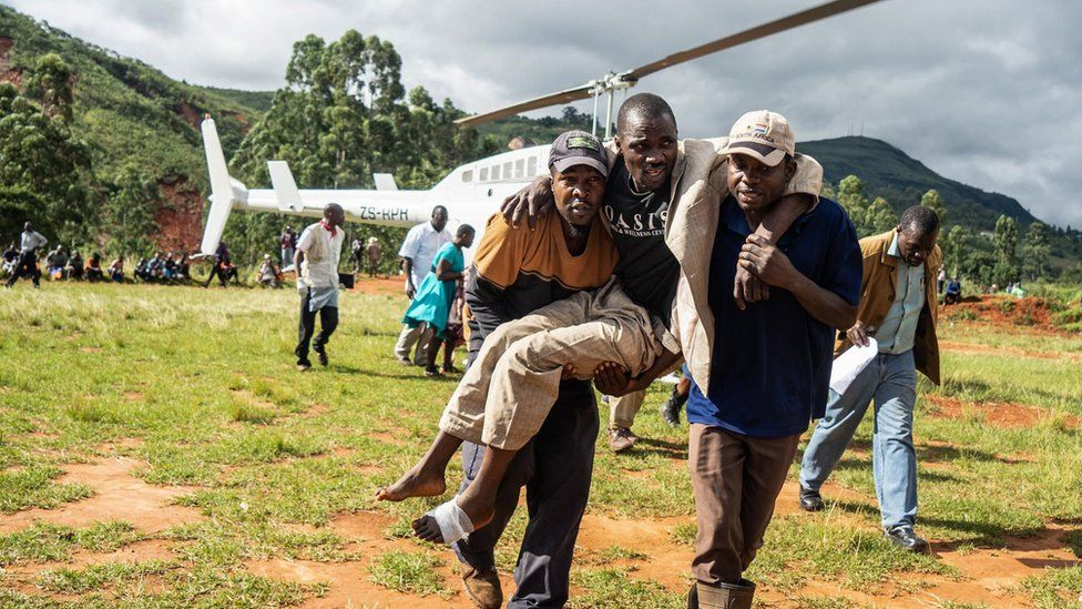 A man injured in the cyclone in Zimbabwe is carried away from a helicopter.