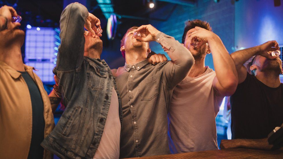 Men drinking shots of alcohol