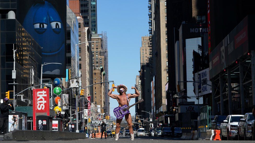 A minor New York celebrity who poses for tourist photos as the Naked Cowboy wears a mask in mostly deserted Times Square