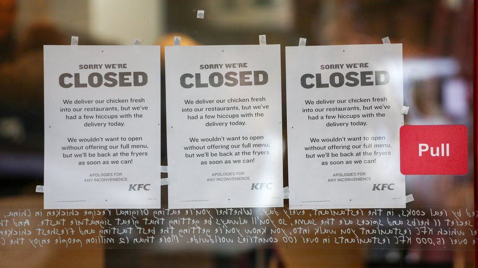 Signs in a KFC shop door which say that the store is closed due to a shortage of chicken