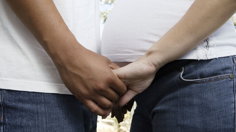 two people hold hands over a pregnant belly