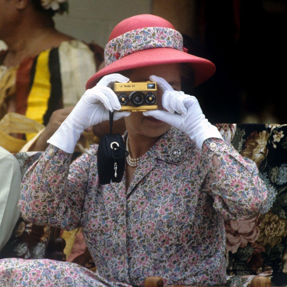 Taking photographs with her gold Rollei camera