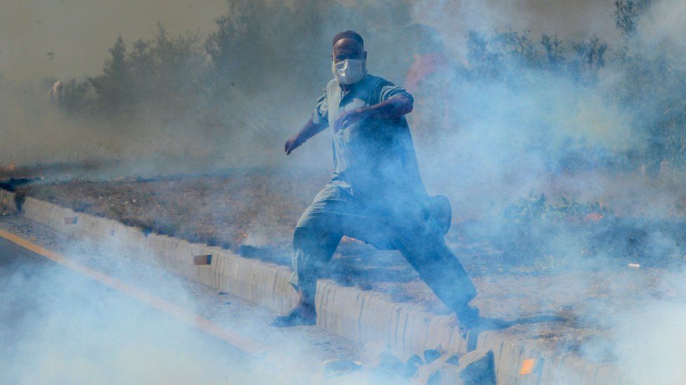 A supporter of Pakistan's former prime minister Imran Khan, runs amid tear gas fired by police during a protest rally in Swabi on May 25, 2022.