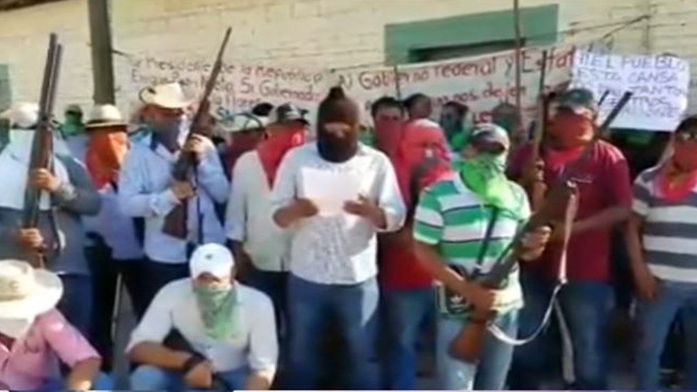 Screenshot of a YouTube video showing masked villagers reading out a communique