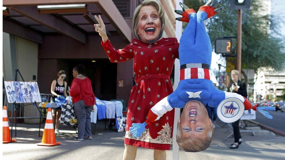 Person in Hillary Clinton mask holds inverted Donald Trump puppet, Phoenix, Arizona, 20 October 2016