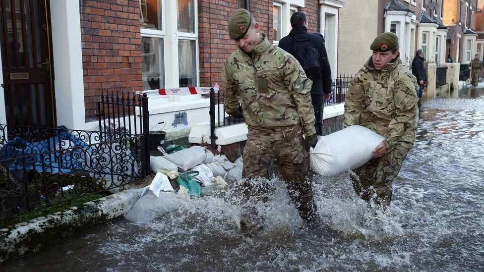 members of the armed forces helping distribute sandbags to residents following flooding in Carlisle