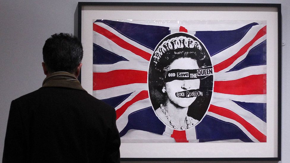 A man views a work depicting Britain's Queen Elizabeth II entitled God Save The Queen (R) by artist Jamie Reid made for British punk band the Sex Pistols in 1977 during 'The Queen: Art and Image' exhibition at the Ulster Museum in Belfast, Northern Ireland on January 14, 2012