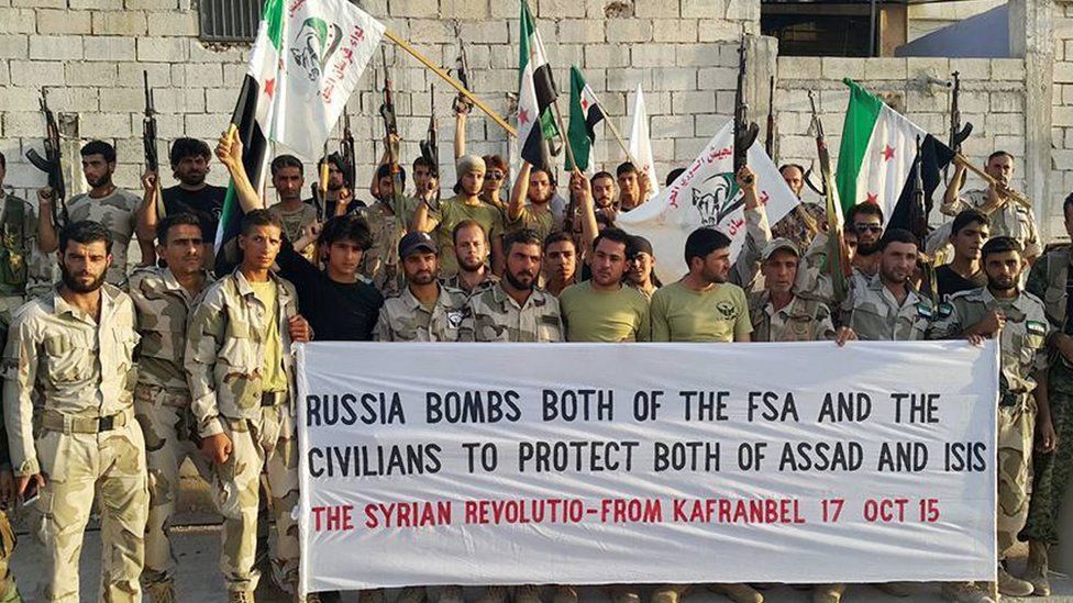 Free Syrian Army fighters of Fursan al-Haq Brigade hold a banner, in Kafranbel, Idlib province, northern Syria