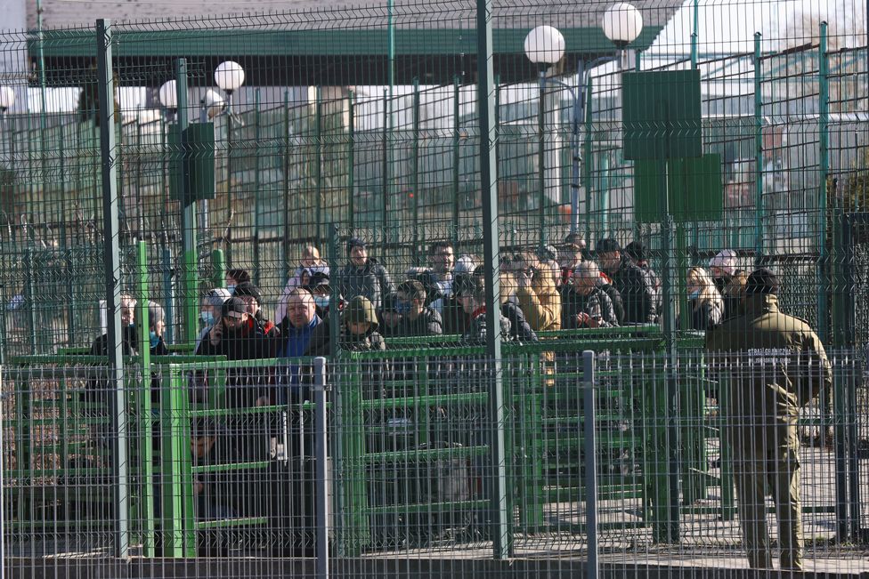 People wait at the Ukrainian side of the border crossing between Poland and Ukraine, as seen from Medyka, Poland, 24 February 2022