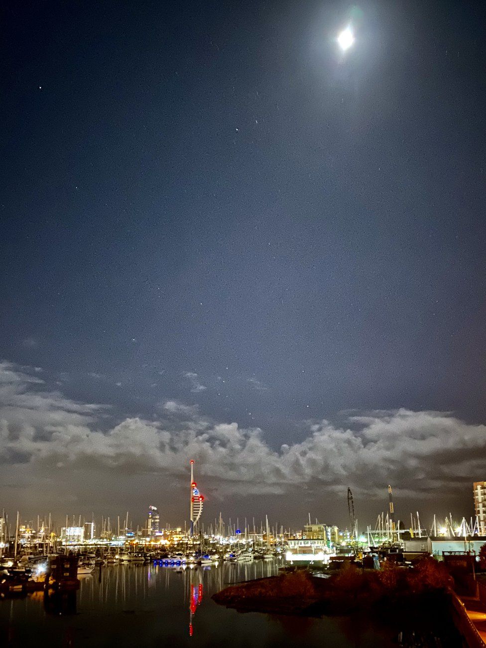 Boats in a harbour under moonlight