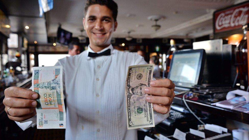 A waiter holds up a five US dollar bill next to five Cuban Pesos in Havana, Cuba, 17 March 2016.