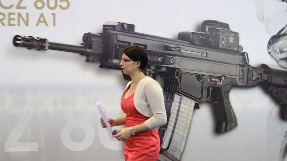 A woman passes a picture of an CZ-805 assault rifle at the booth of Czech firearm producer Ceska Zbrojovka during the International Exhibition of Defence and Security Technologies (IDET) in Brno, Czech Republic (22 May 2013)