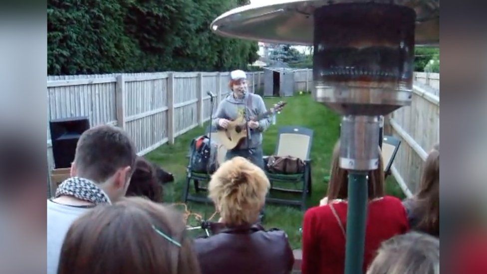 Ed Sheeran performing in a garden