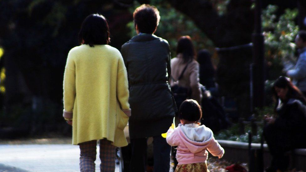 This picture taken on 12 December 2015 shows a family strolling at a park in Tokyo. Japan's top court will rule this week on a pair of 19th Century family laws that critics blast as sexist and out of touch