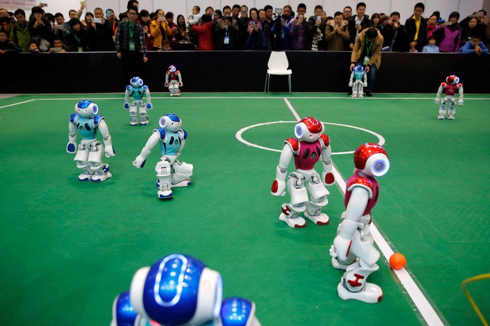 Visitors watch robot teams competing for the ball during a robot performance during the World Robot Conference